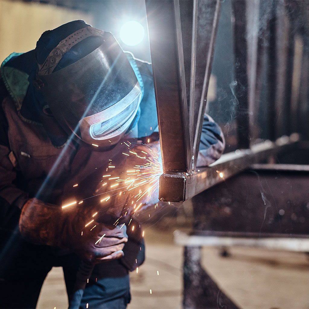 Mann schweißt an einer Stahlkonstruktion