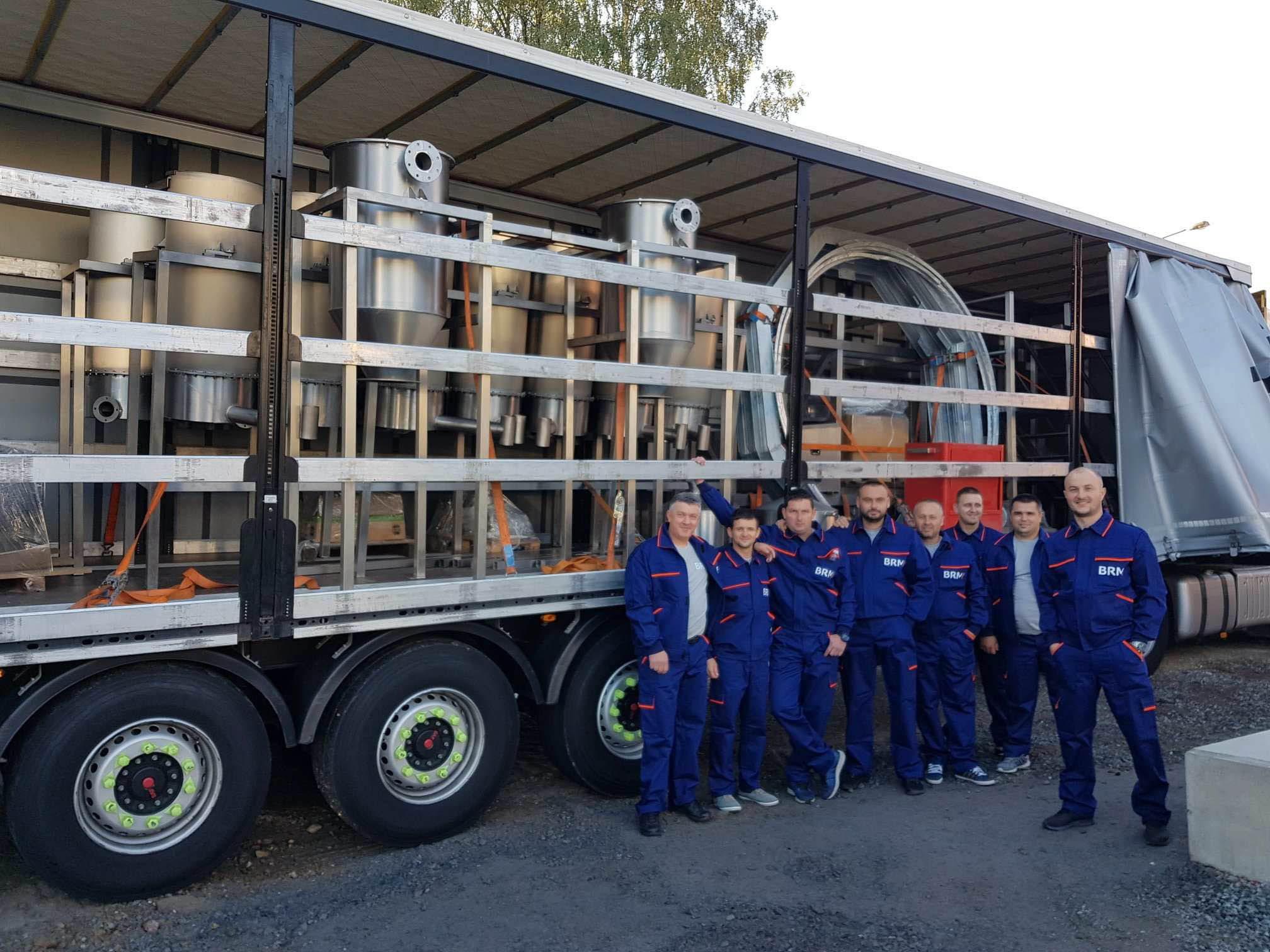 BRM Team in Arbeitskleidung vor einem mit Maschinen beladenen LKW